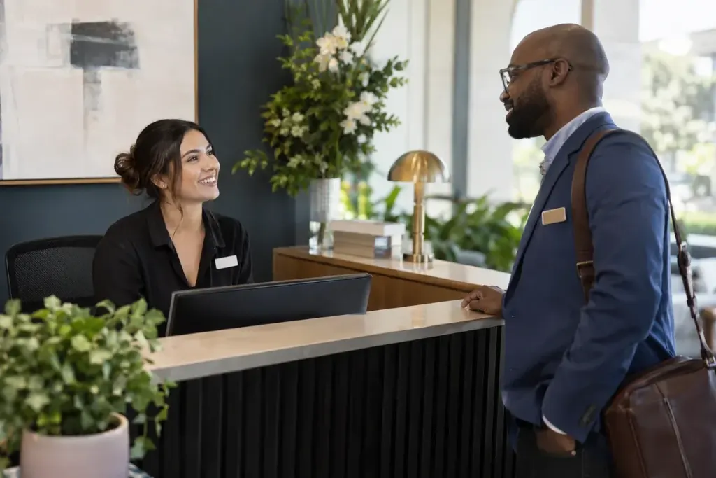 Two coworkers meeting at a reception desk wearing plain unlettered name badges.
