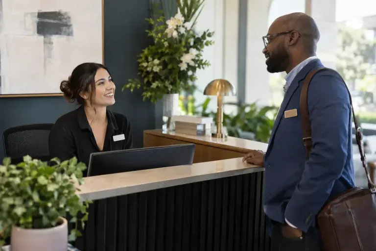 Two coworkers meeting at a reception desk wearing plain unlettered name badges.